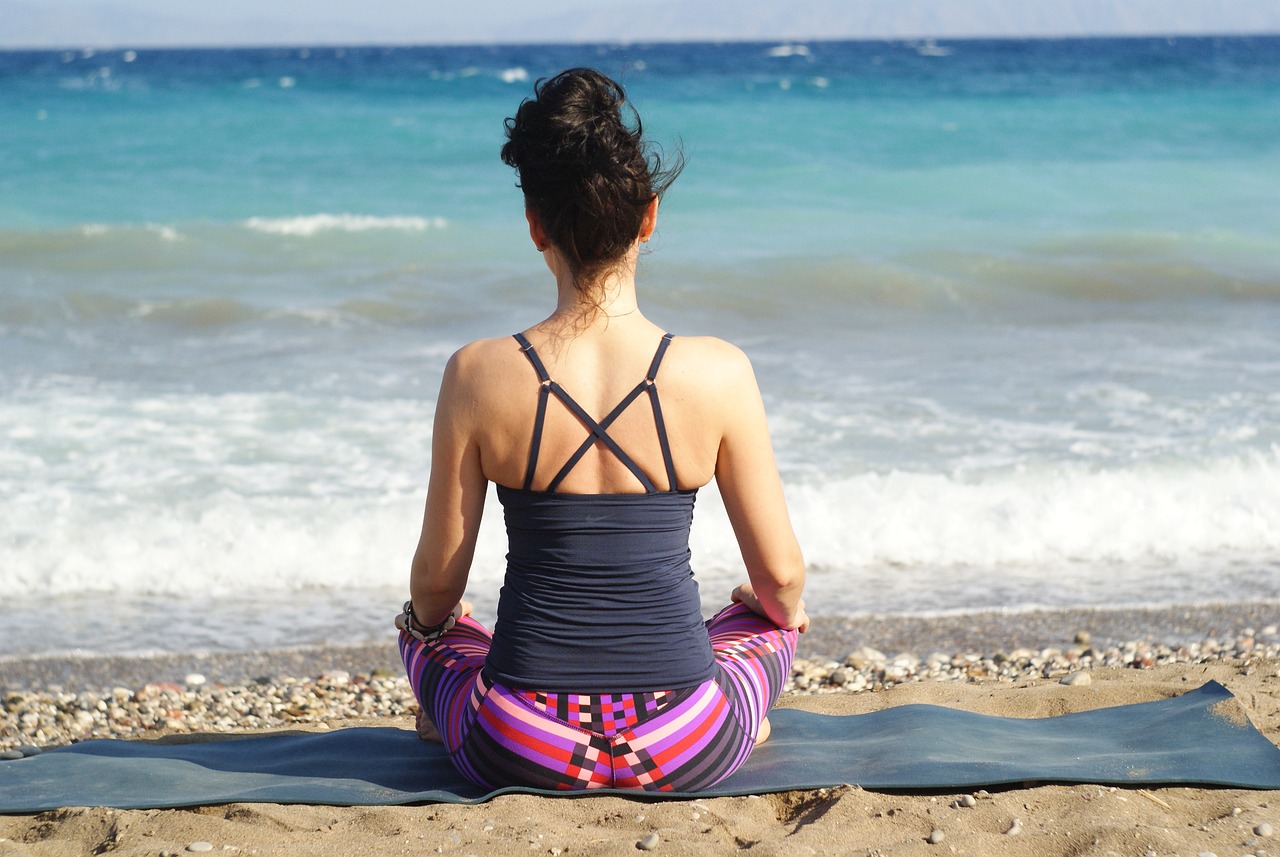 Femme seule pratiquant la méditation à la plage, face à la mer